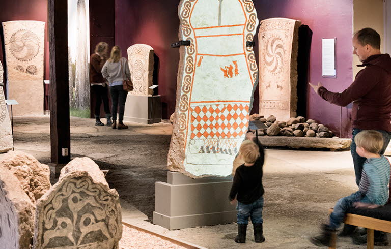 Familj tittar på gotländska bildstenar på Gotlands museum.