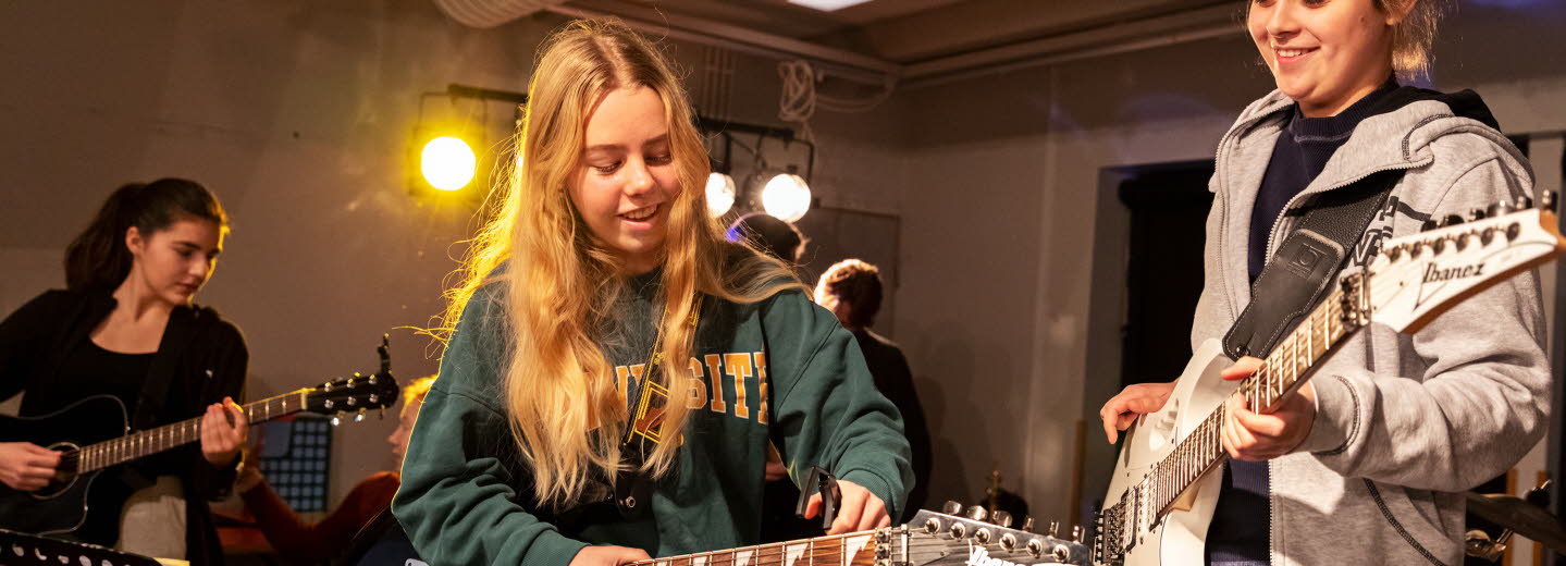 Tre tjejer spelar elgitarr.