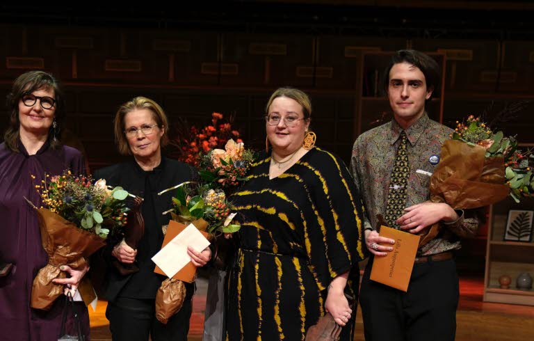 The four laureates stands together with flowers in their hands.