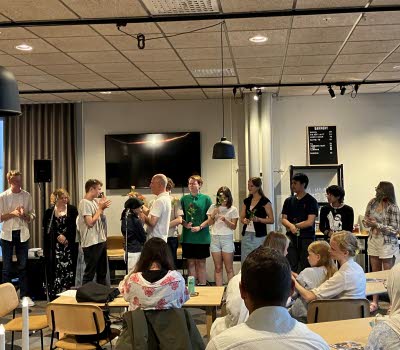 Ungdomar med blommor i händerna står uppradade framför en publik.