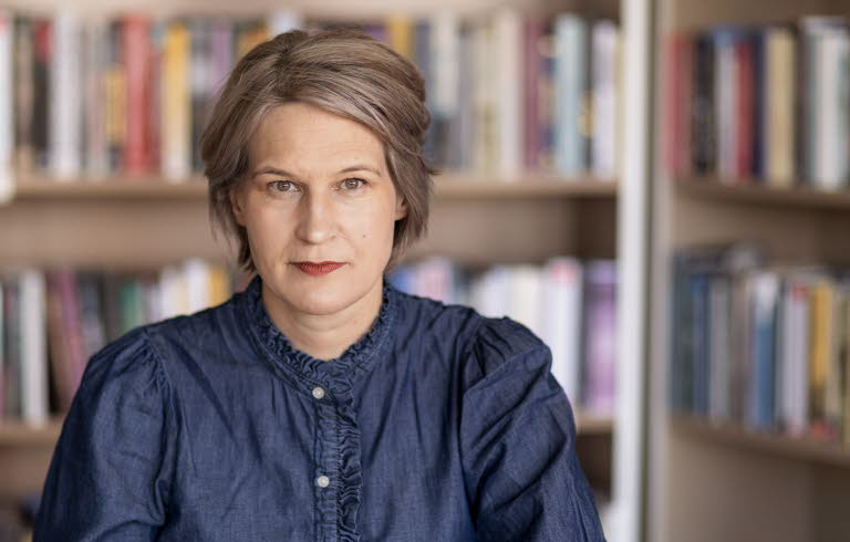 Porträttfotografi av en medelålders kvinna, Kulturrådets generaldirektör. I bakgrunden bokhyllor med böcker.