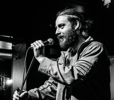 Photo of christian on stage talking into a microphone.