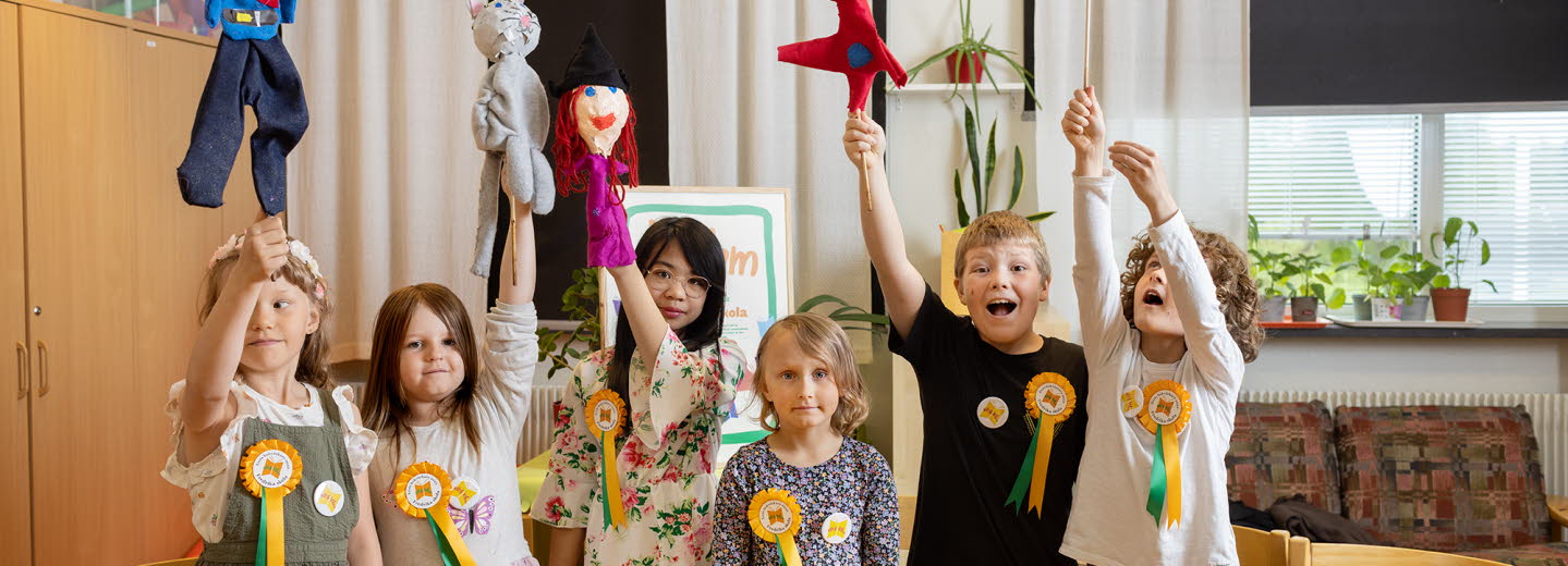 Sex barn, såväl pojkar som flickor, håller upp händerna, har prisrosett fastsatta på sina tröjor.