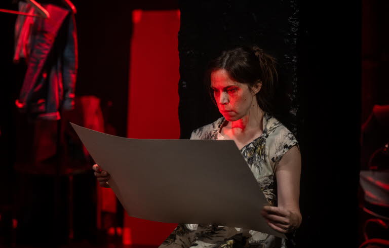 Läsande sittande kvinna belyst av rött ljus.