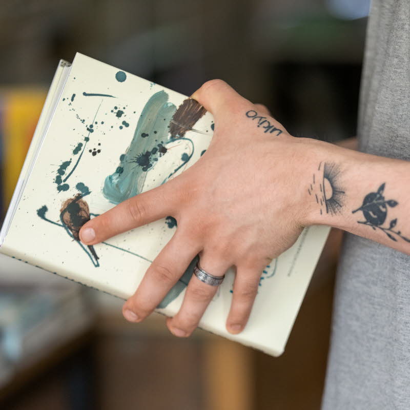Tatuerade armar som håller i en bok.