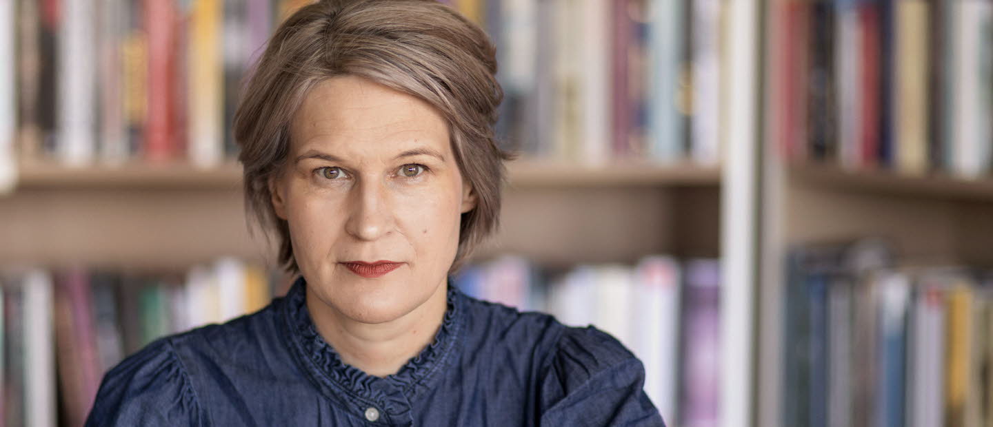 Porträttfotografi av en medelålders kvinna, Kulturrådets generaldirektör. I bakgrunden bokhyllor med böcker.