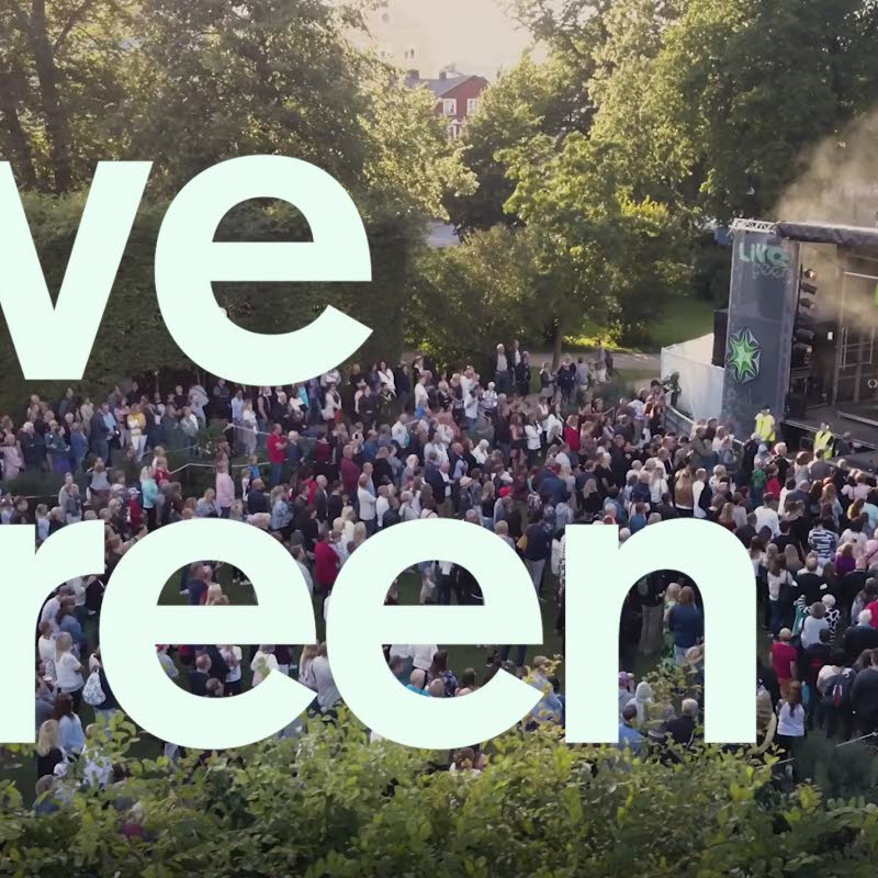Text med LiveGreen, i bakgrunden en utomhusscen med publik.