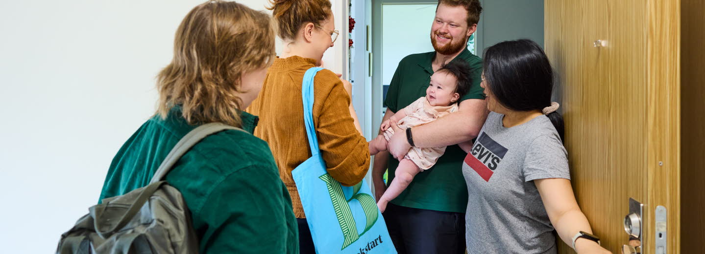 Två medarbetare som arbetar med Bokstart gör ett hembesök. Möter en familj i trapphuset.