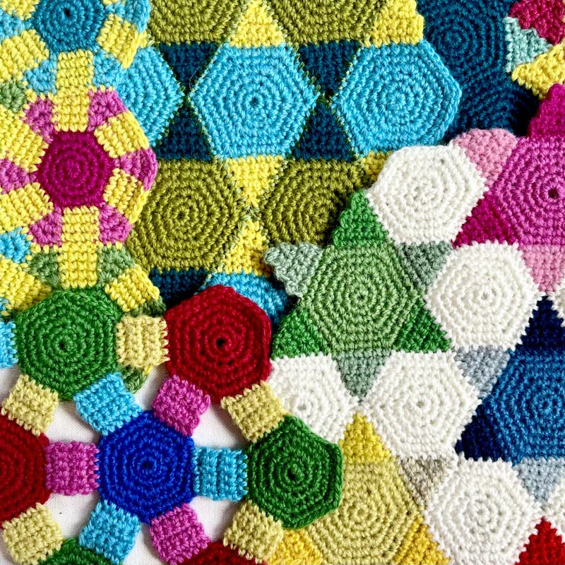 Färgglad virkad textil med geometriska mönster i olika former och färger.