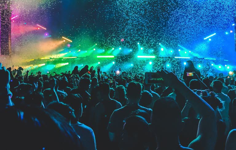 Publikhav framför konsertscen med färgsprakande landskap som scenografi.