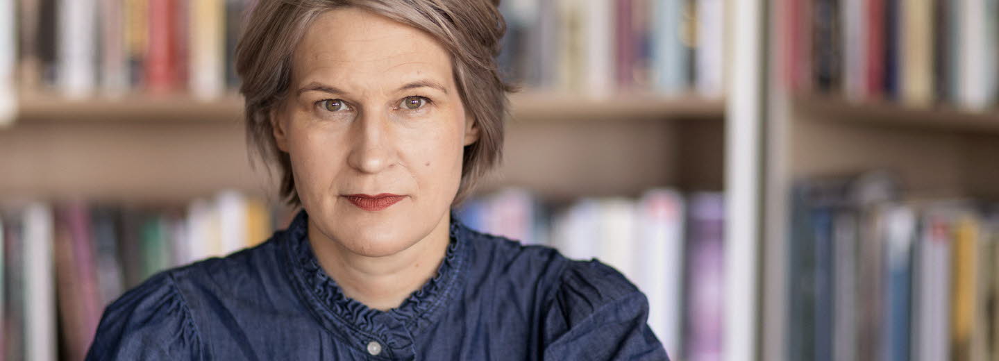 Porträttfotografi av en medelålders kvinna, Kulturrådets generaldirektör. I bakgrunden bokhyllor med böcker.