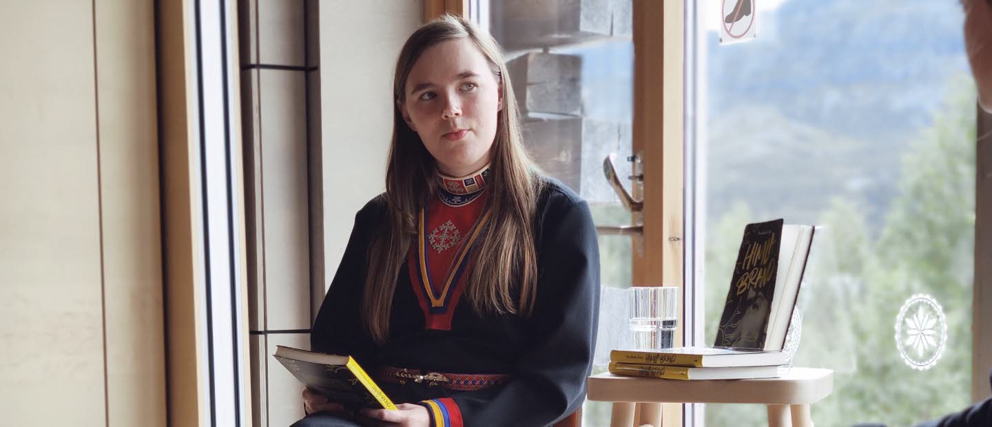 Kvinna samtalar vid fönster.