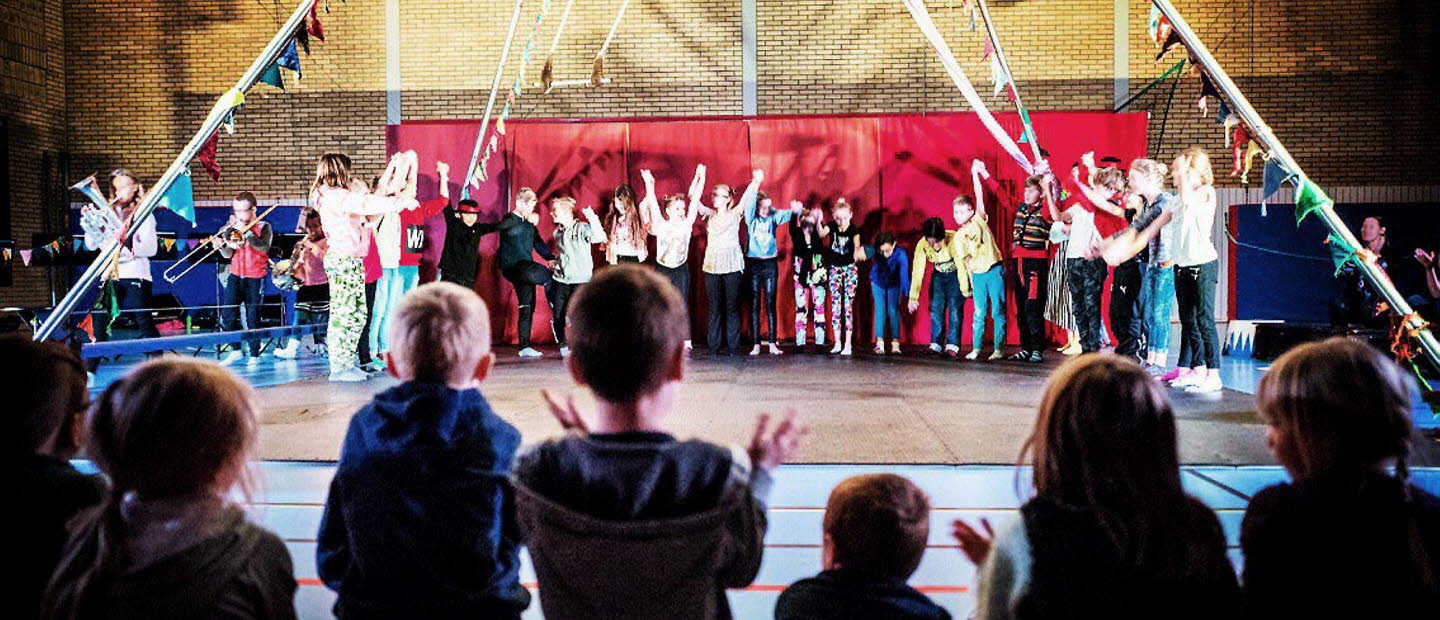 Barn uppträder med cirkus på en scen