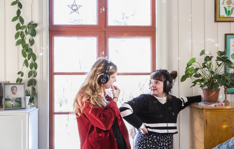  Två unga kvinnor med hörlurar som tittar på varandra.