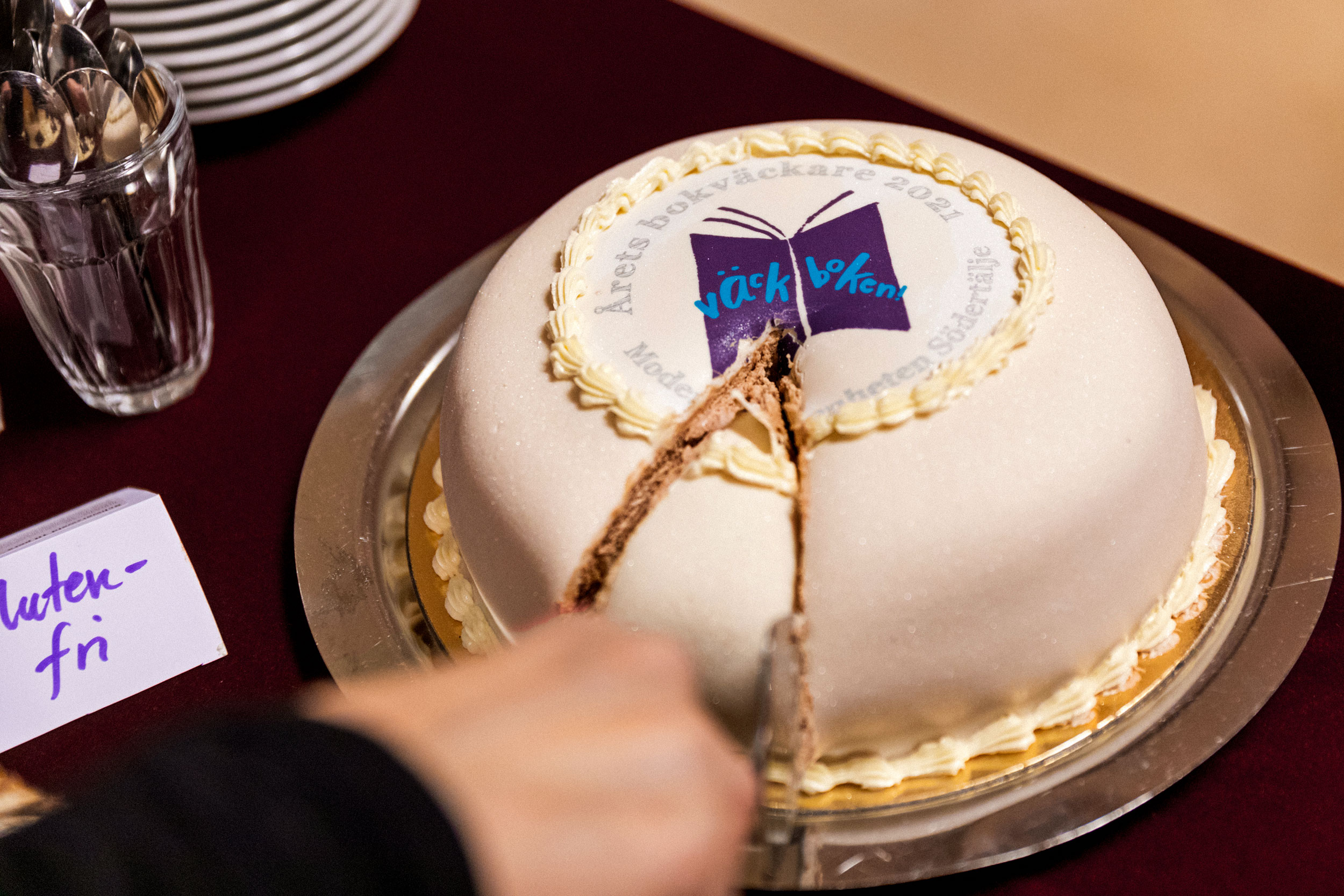Tårta med Väck boken-logotyp skärs upp.