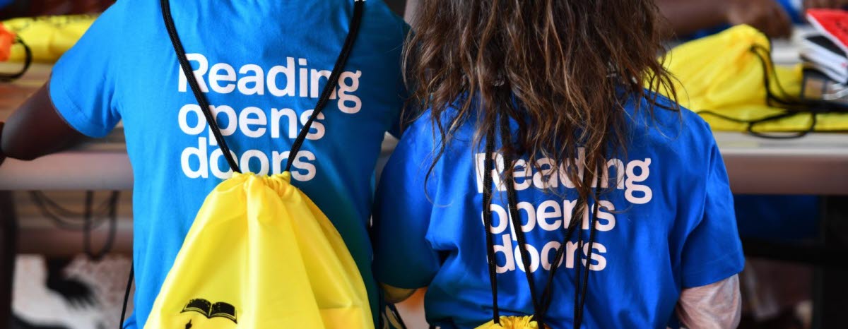 Two children with t-shirts that says "Reading opens doors"