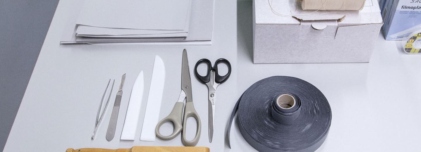 Bord med olika föremål som sax, tejp, borste, anteckningsblock.