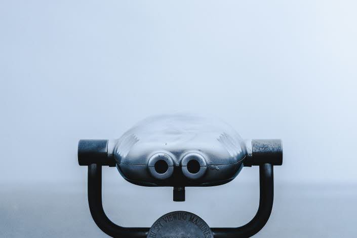 Foto av en kikare i fören på en båt. Dimmigt hav i bakgrunden. 