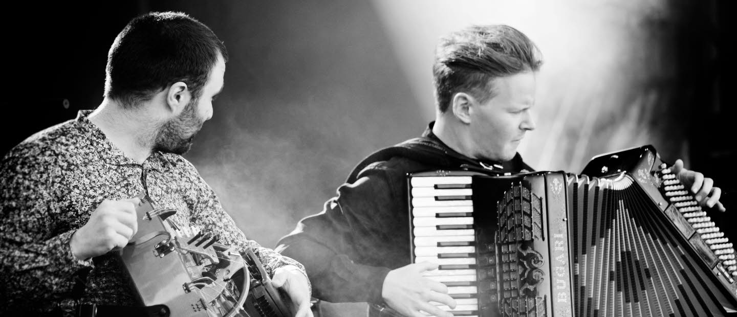 Concert with the music group Symbio, one man is playing the accordion and the other man is playing Hurdy-Gurdy. Black and white photo taken by Sona Hellman.