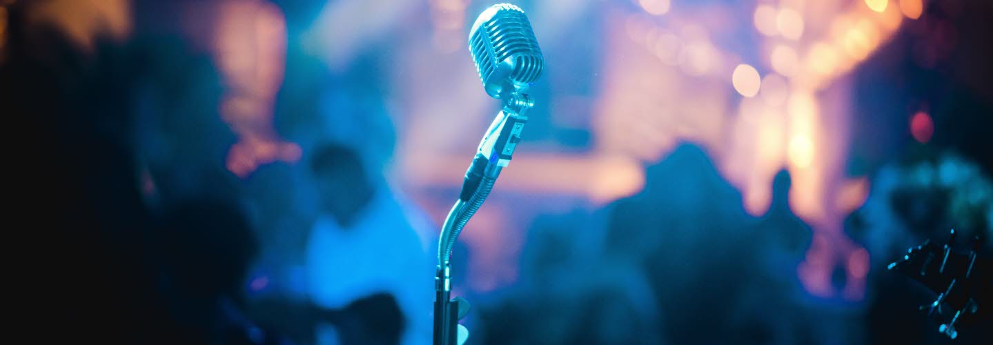 Närbild på mikrofon mot ett publikhav.