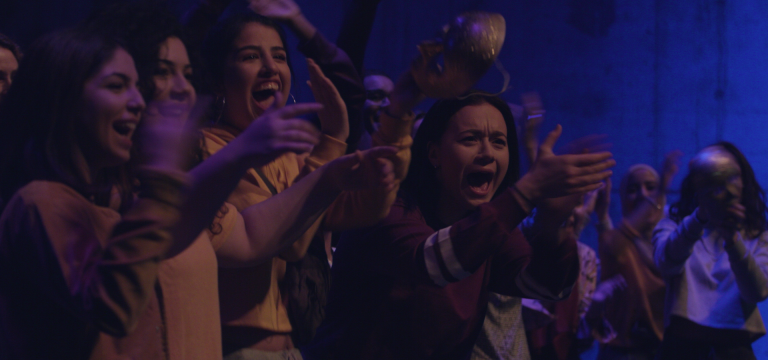 Del av en ung engagerad publik som klappar händer och sjunger.