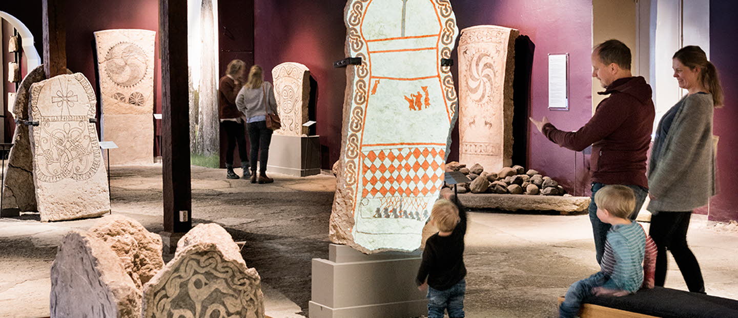 Familj tittar på gotländska bildstenar på Gotlands museum. 