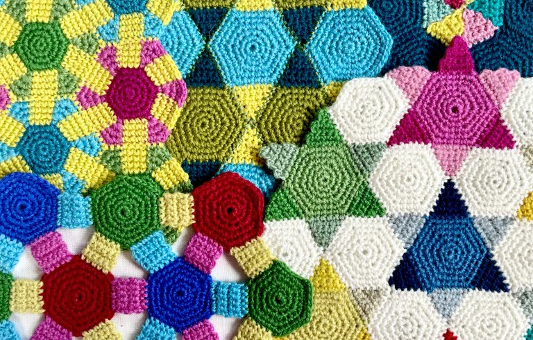 Färgglad virkad textil med geometriska mönster i olika former och färger.