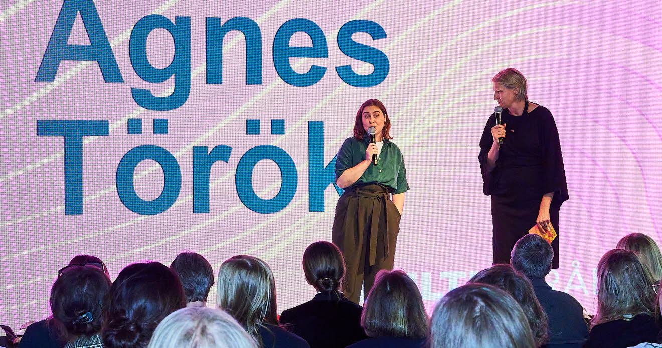 Två personer samtalar på en scen.