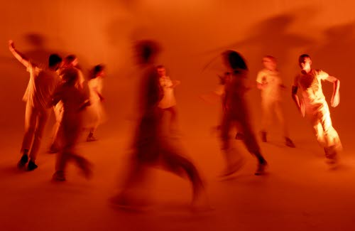 Blurriga dansare upplysta i brungula toner springer i en cirkel.