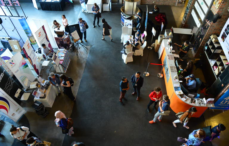 Foto taget ovanifrån på ett golv fyllt av människor och informationsbord.