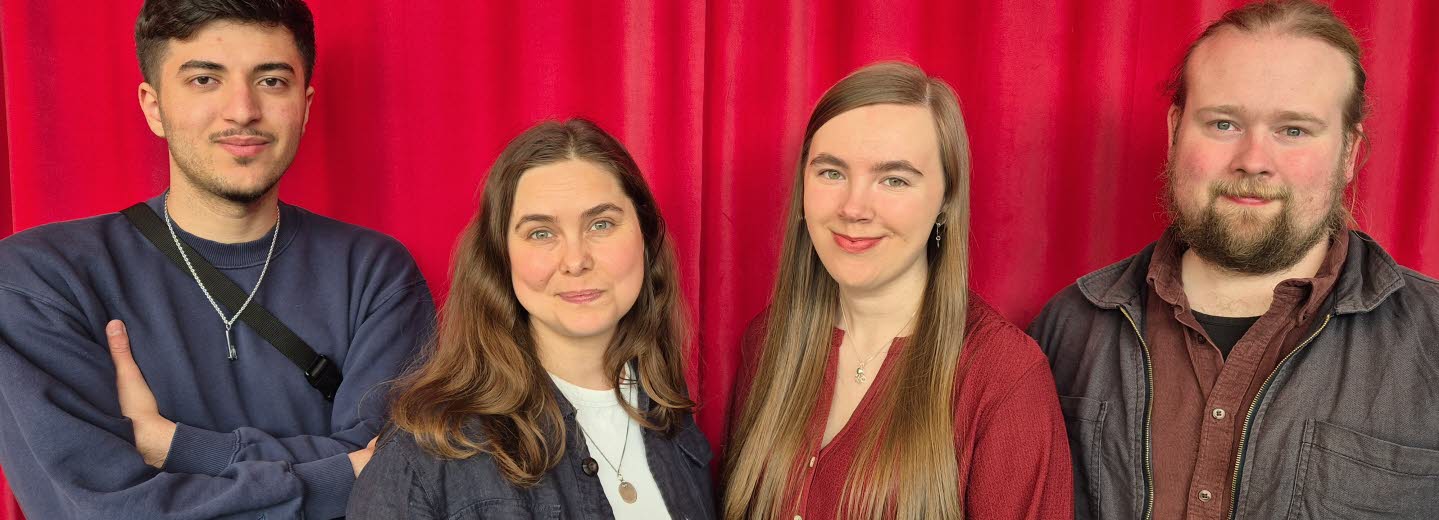 Gruppbild av två kvinnor och två män framför ett rött draperi. 