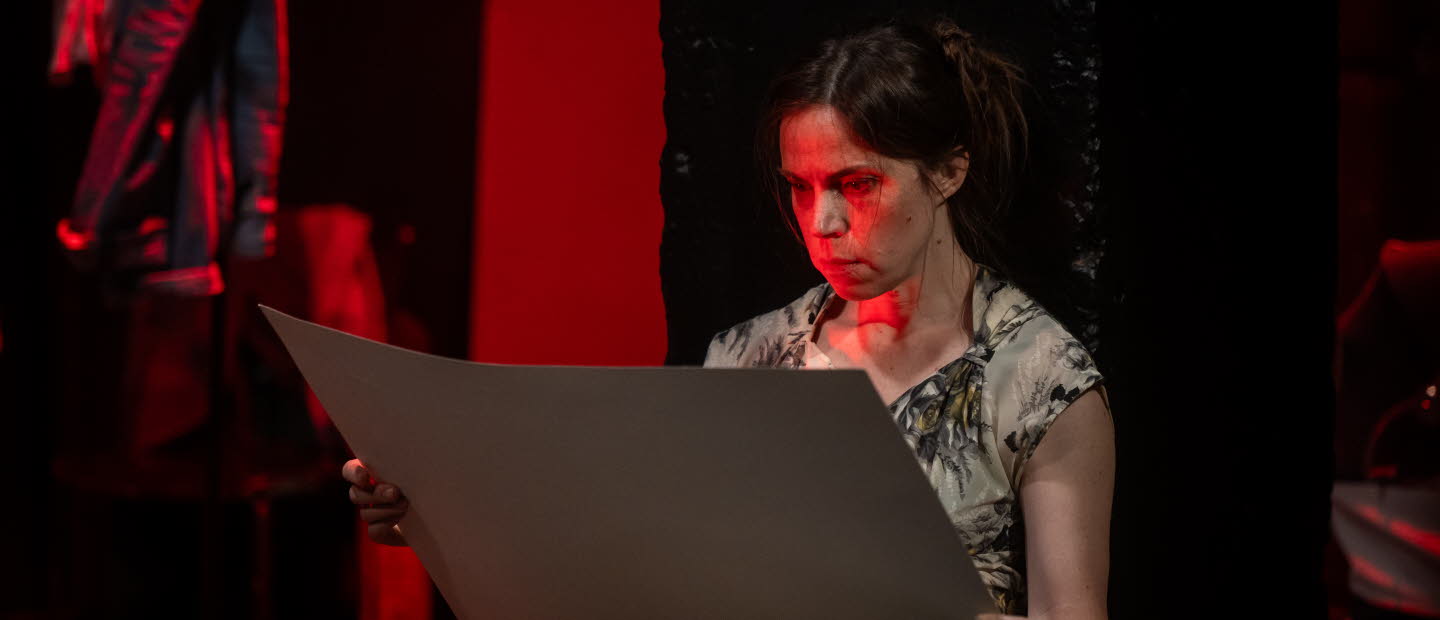 Läsande sittande kvinna belyst av rött ljus.