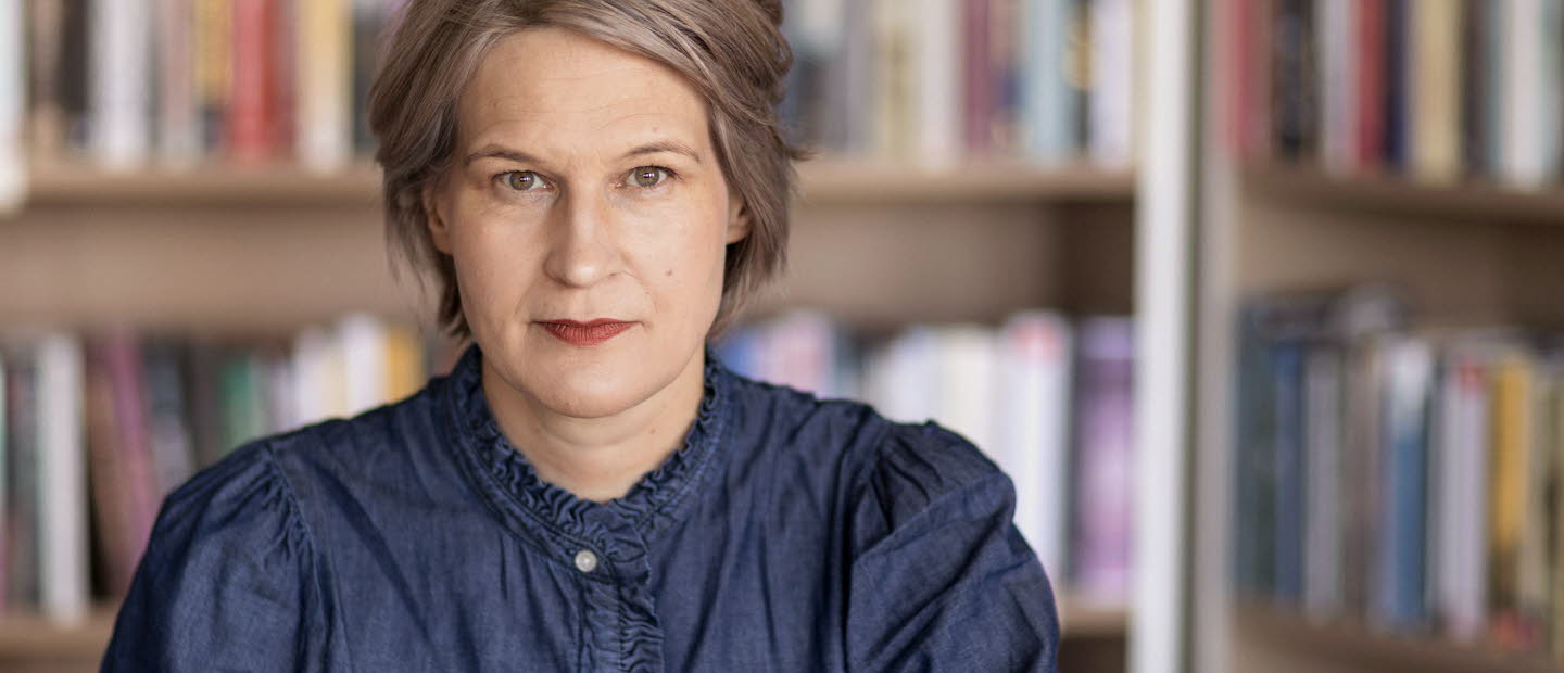 Porträttfotografi av en medelålders kvinna, Kulturrådets generaldirektör. I bakgrunden bokhyllor med böcker.