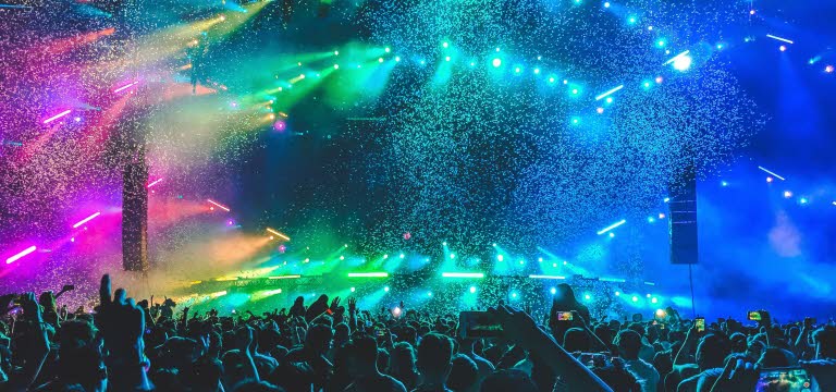 Publikhav framför konsertscen med färgsprakande landskap som scenografi.