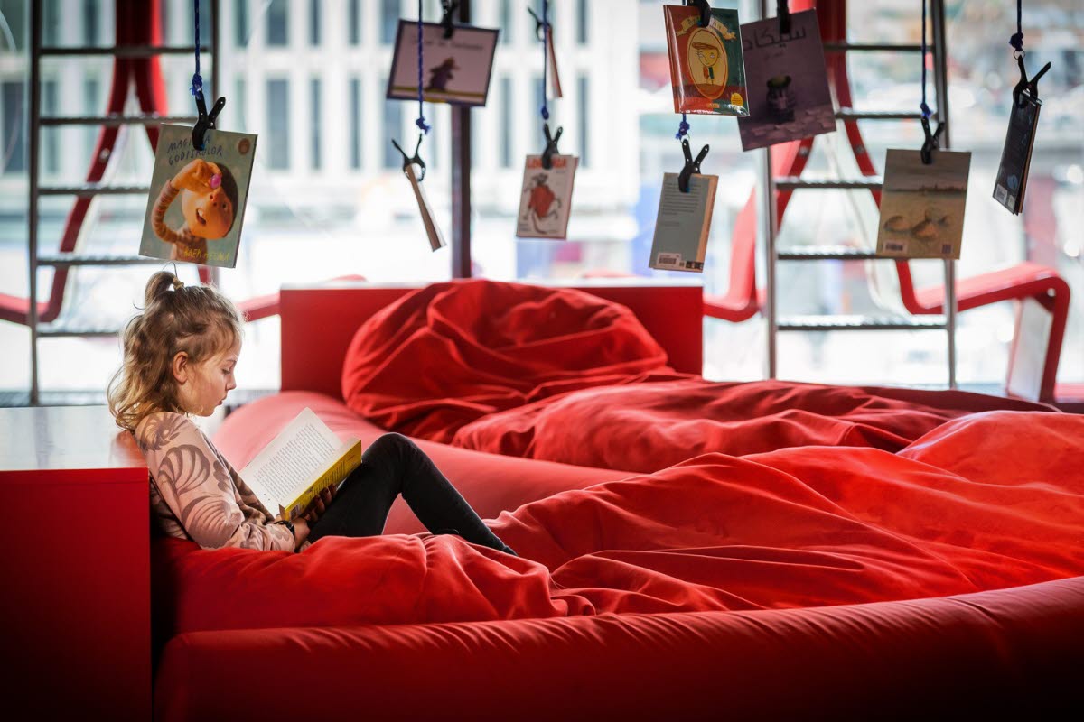 Ett barn ligger i en soffa och läser en bok,