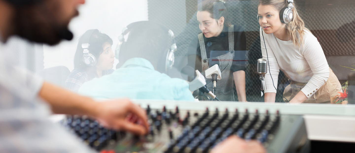 Radioinspelning. Man vid mixerbord och tre tjejer och en man samtalar med mikrofoner och headsets.