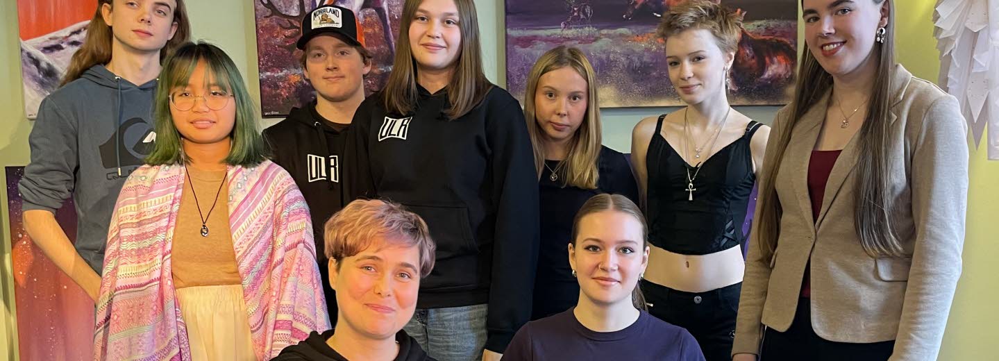 Två personer sitter på knä och sju personer står runt omkring dem.