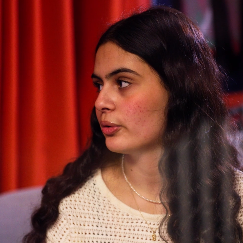 En kvinna som står framför ett draperi.