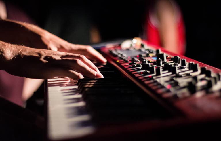 Närbild på händer som spelar keyboard i en studio.