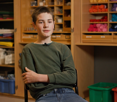 En pojke sitter på en stol i en intervjusituation.