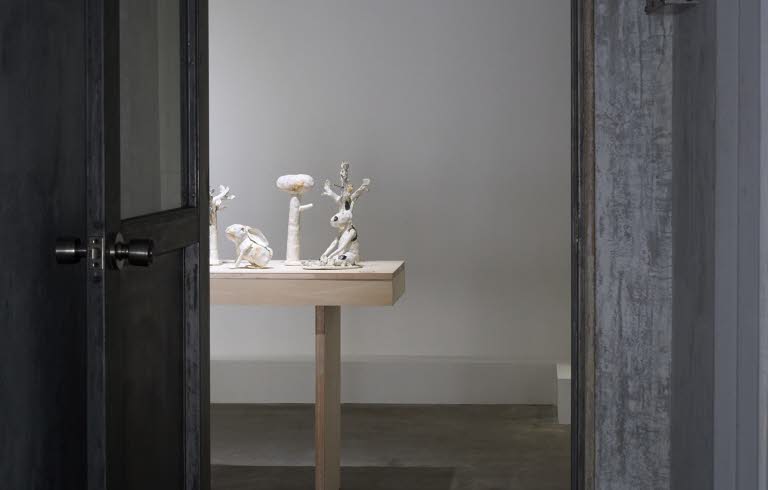 En dörr står öppen, i rummet skymtas vita skulpturer uppradade på ett bord.