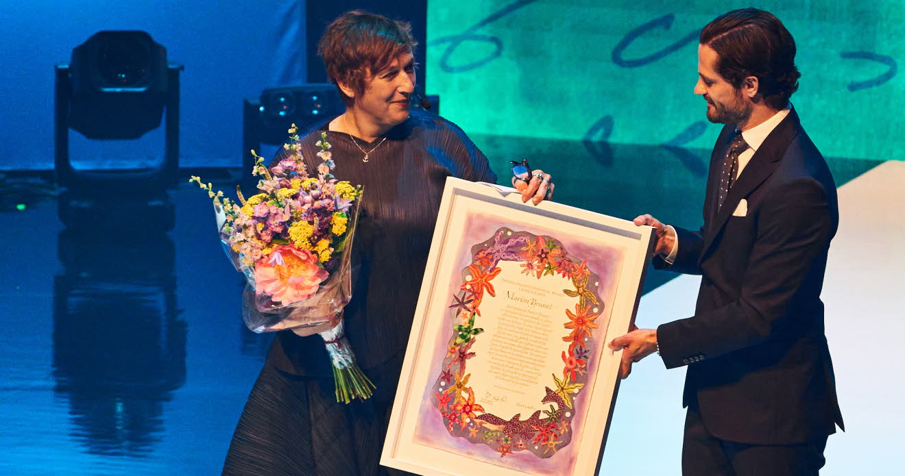 Marion Brunet står på en scen tillsammans med H.K.H. Prins Carl Philip.
