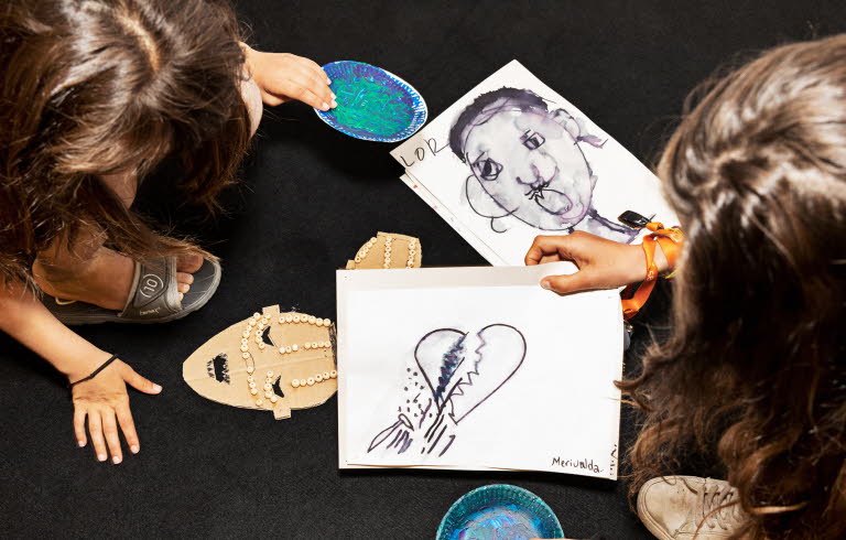 Två personer uppifrån som har teckningar framför sig, med bland annat ett brustet hjärta.