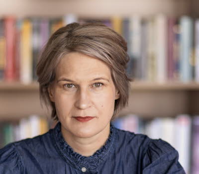 Porträttfotografi av en medelålders kvinna, Kulturrådets generaldirektör. I bakgrunden bokhyllor med böcker.