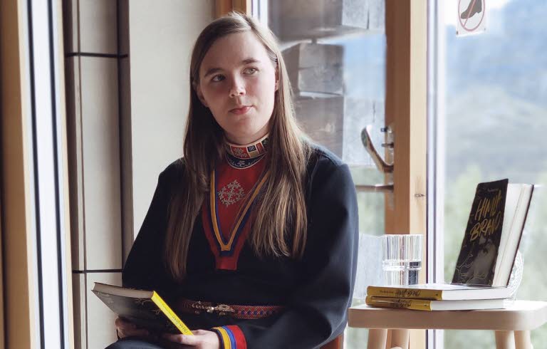 Kvinna samtalar vid fönster.