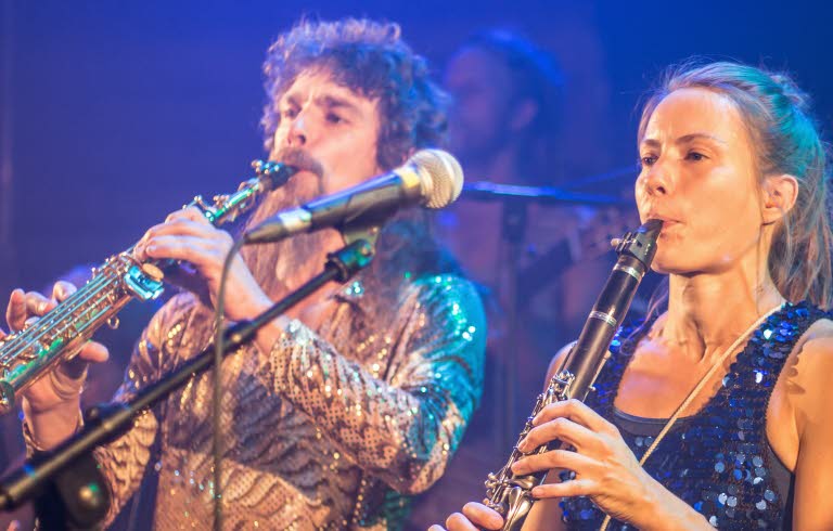 Del av en musikensemble: en man och en kvinna som spelar blåsinstrument.