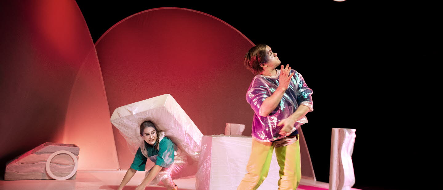 Två skådespelare på en scen med madrasser och ringar.
