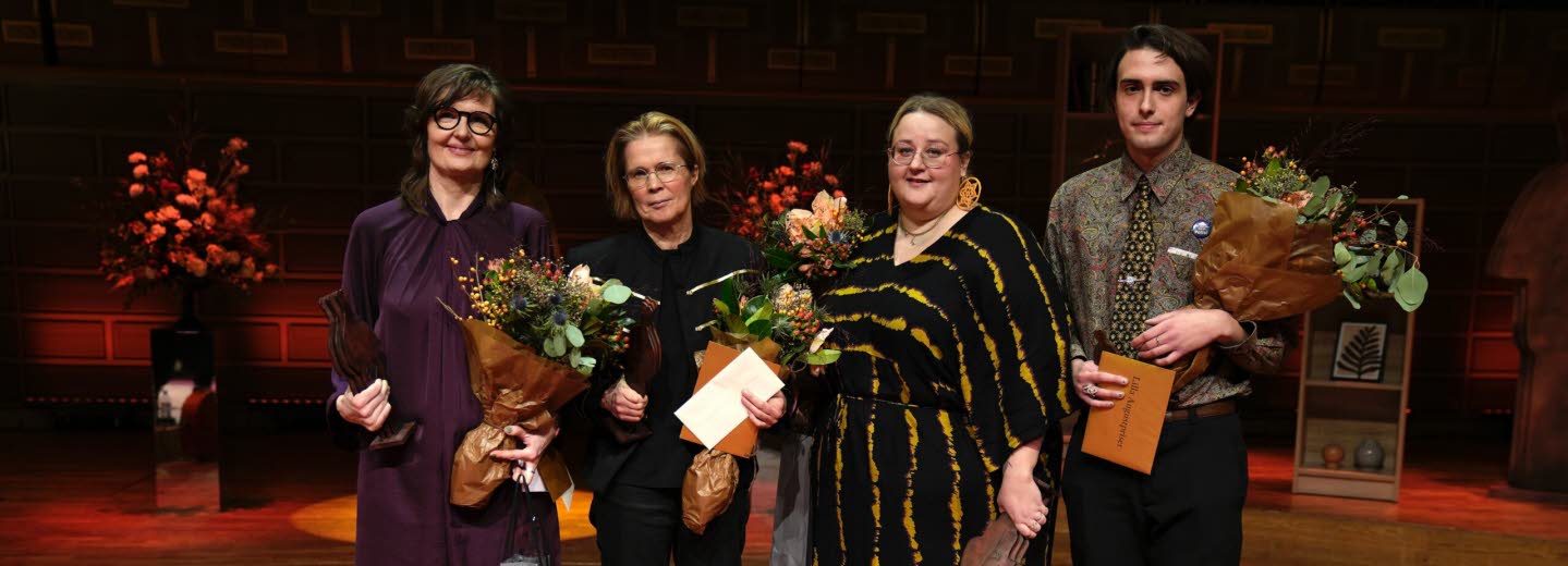 The four laureates stands together with flowers in their hands.