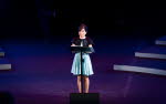 Kvinna står vid ett talarpodium på en scen