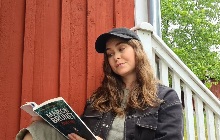 Läsambassadören läser en bok på en trappa.